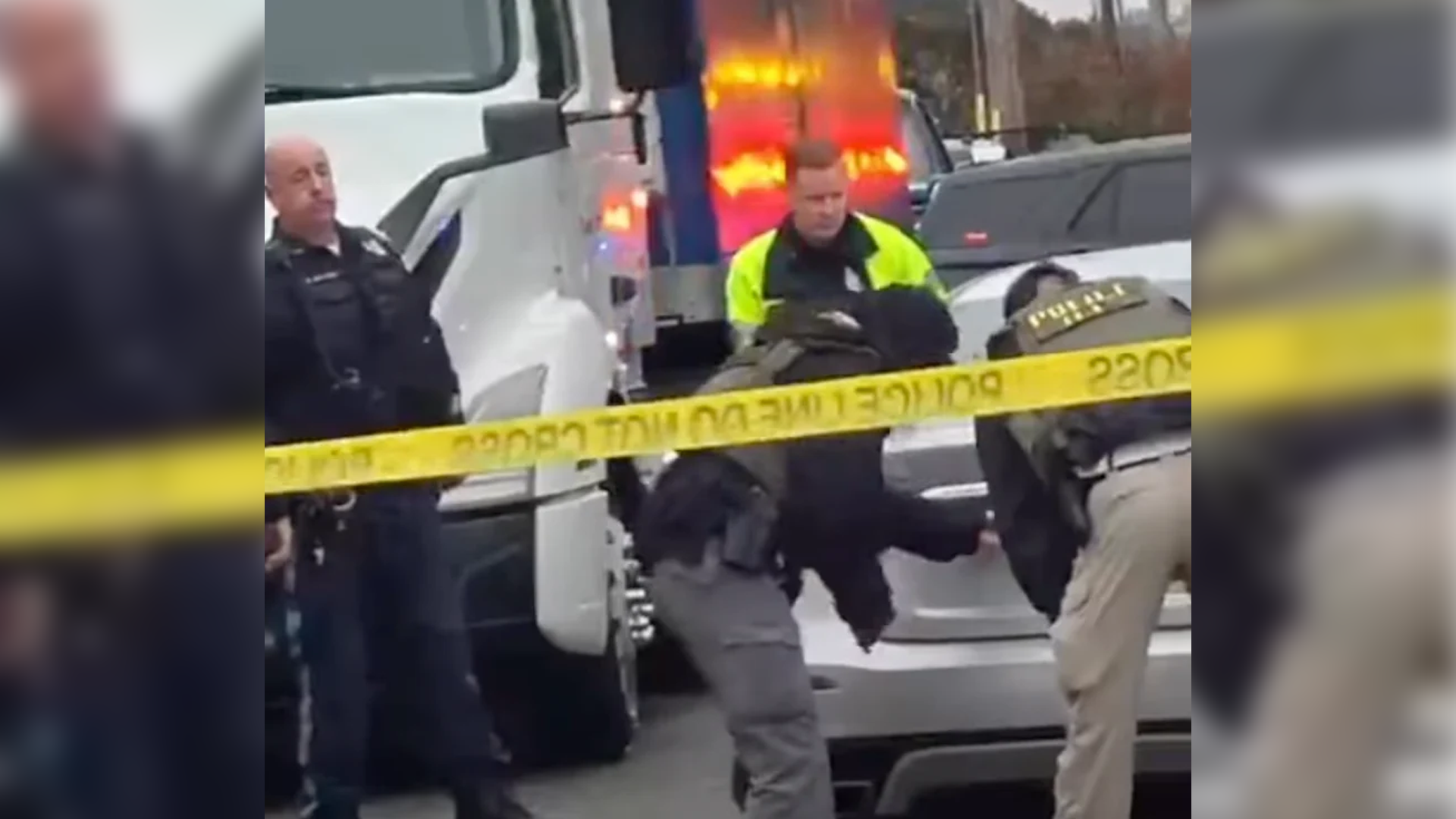 Law enforcement officers and federal agents gather behind police tape near vehicles at an apparent arrest scene in Red Bank, New Jersey.